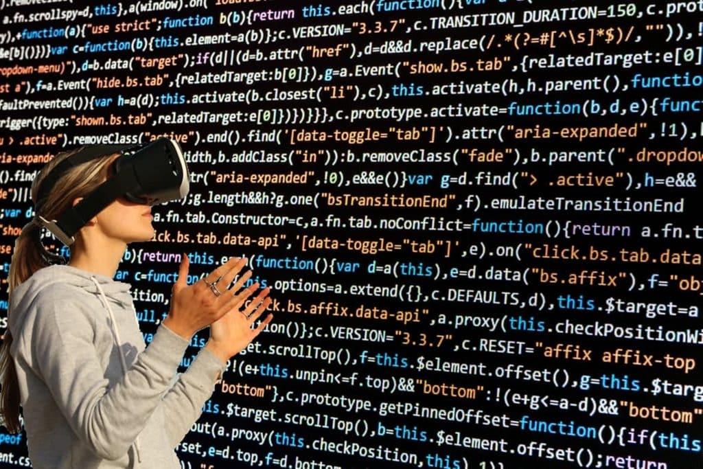 How UK SMEs Are Using Virtual Data Rooms to Speed Up Funding Rounds Person wearing a virtual reality headset, reaching toward a wall of colorful code on a dark background.