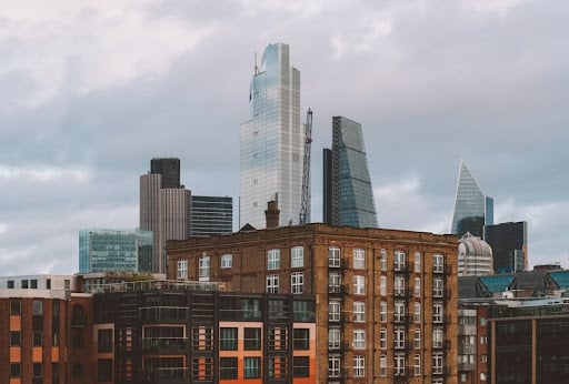 How Construction Consultants in London Help Deliver Successful Building Projects City skyline with modern glass skyscrapers rising behind a row of red brick buildings in the foreground.