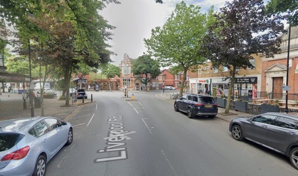 Elderly passenger seriously injured in Liverpool Road collision as police launch CCTV appeal Street view on Liverpool Road with parked cars, trees along the sidewalk, and brick storefronts on the right, including a Spar.