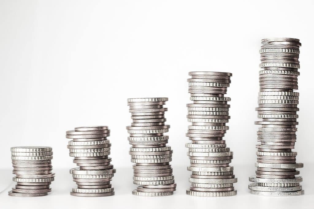 Stacks of silver coins arranged in varying heights on a white background, suggesting savings or wealth growth.