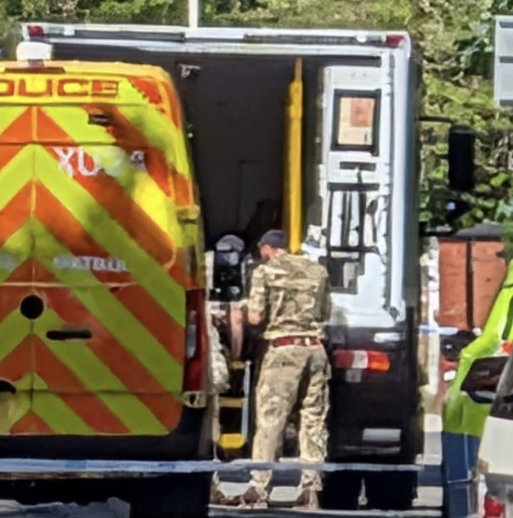Bomb squad called to house clearance on Balfour Road Rear view of a high-visibility emergency vehicle with orange chevron pattern; personnel in camouflage nearby.
