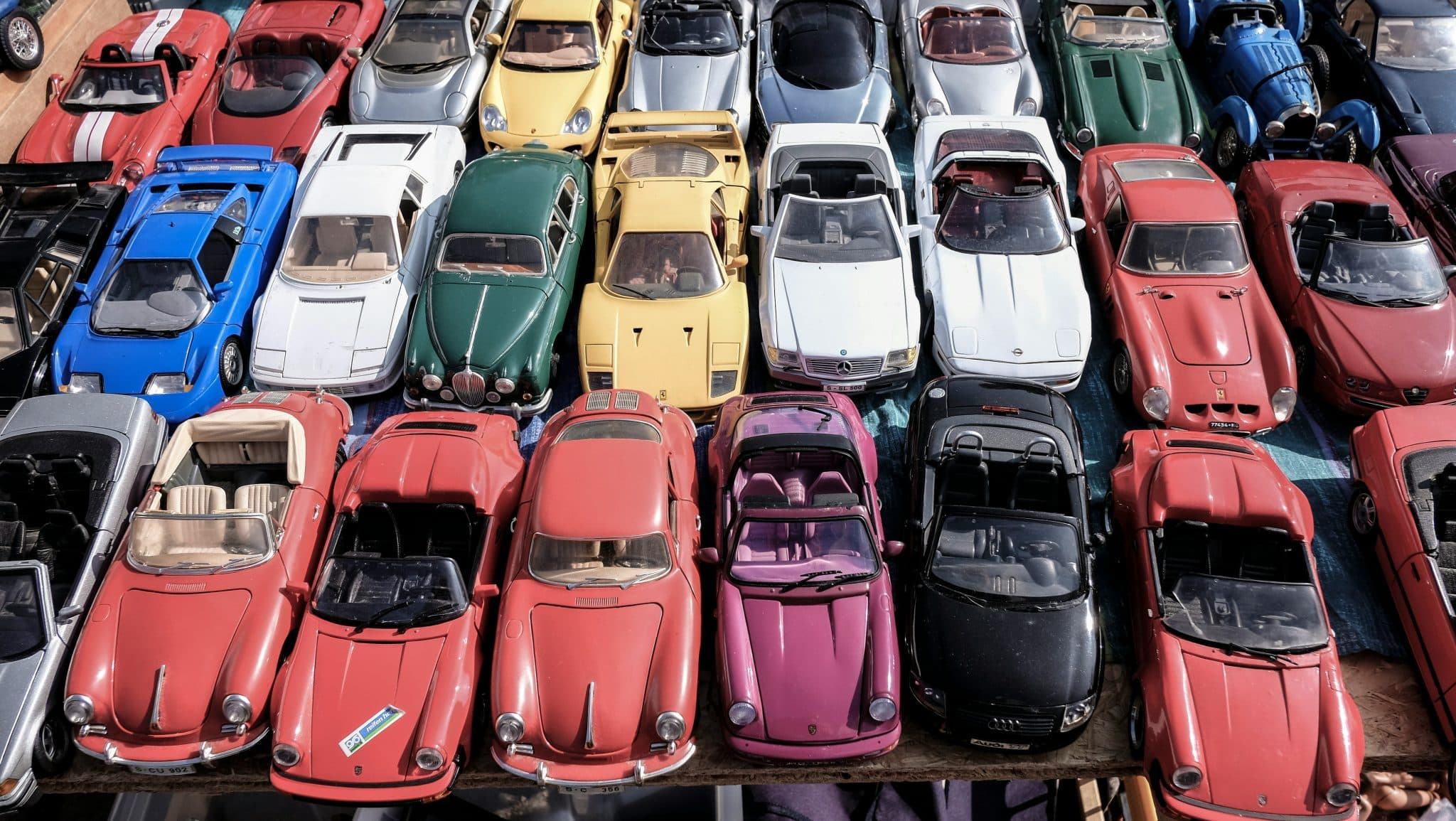 Aerial view of a colorful grid of vintage sports cars parked closely together in rows.