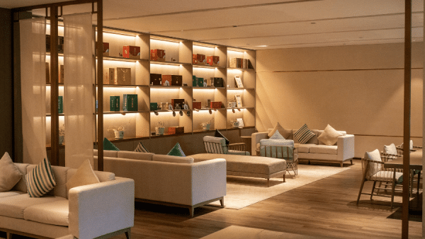 Modern hotel lounge with white sofas, throw pillows, and a wall of lit shelving filled with books when in use as a reading area. (Note: This alt describes purpose and setting.)